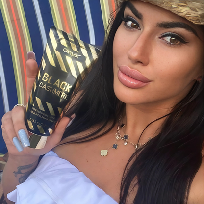 Kobieta trzymająca Onyx Black Cashmere – bronzer do ciała o luksusowej formule zapewniającej ciemny efekt opalenizny i pielęgnację skóry.