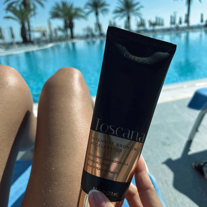 Kobieta trzyma balsam Onyx Toscana przy basenie, w tle woda i palmy, widoczne opalone nogi i tubka produktu w granatowo-złotym kolorze