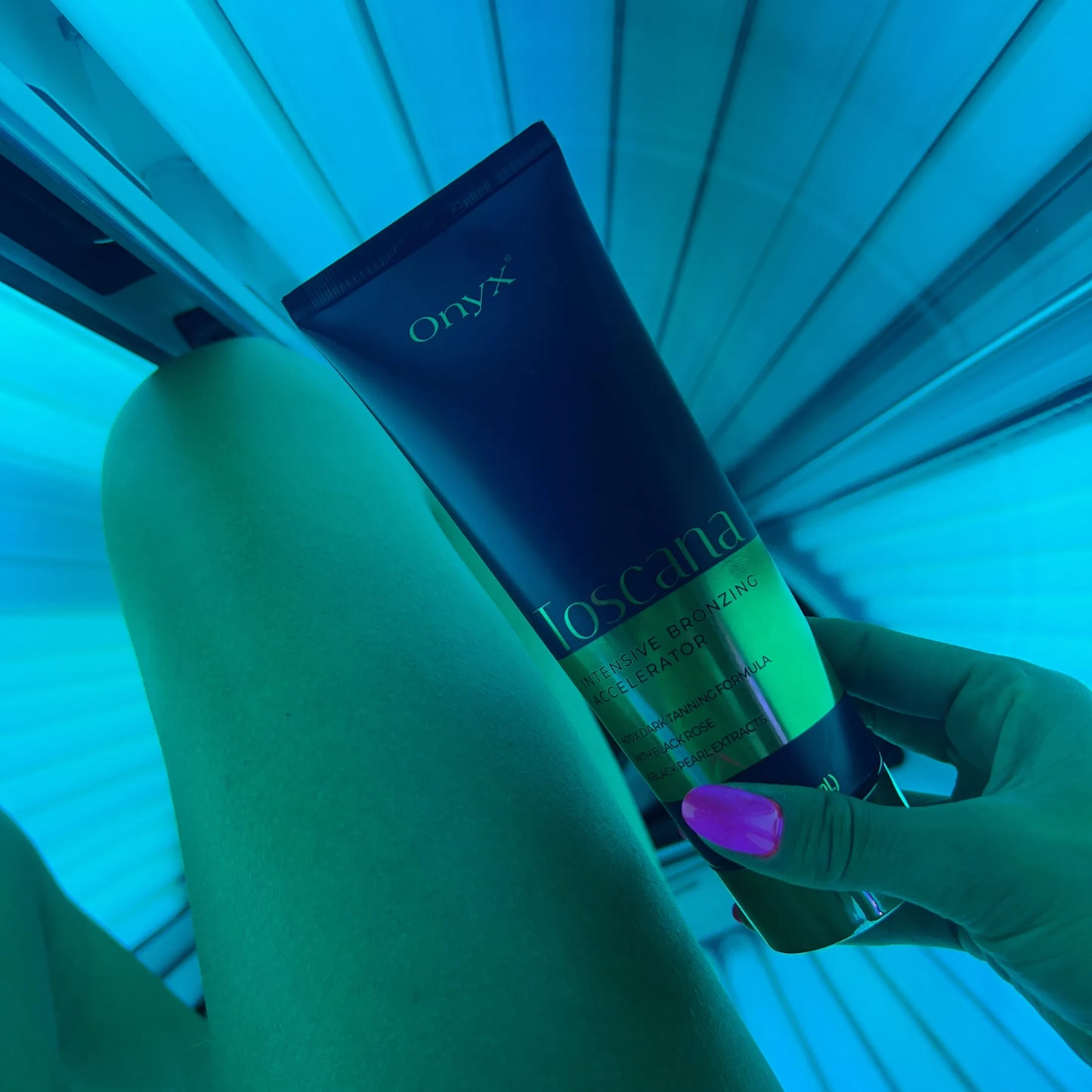 Kobieta trzyma balsam Onyx Toscana w solarium z niebieskim światłem, produkt o formule z czarną różą i ekstraktem z czarnej perły